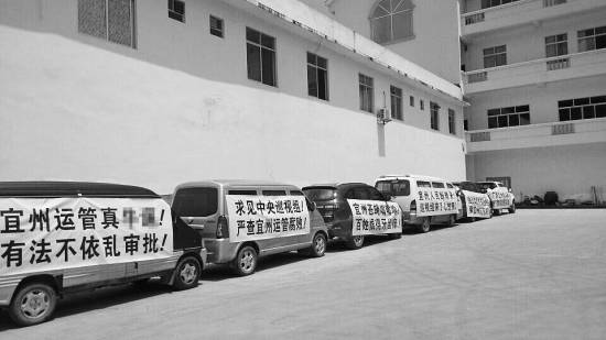 今年7月，宜州市運(yùn)管局通過了當(dāng)?shù)亓硪患臆嚈z企業(yè)開展?fàn)I運(yùn)車輛綜檢業(yè)務(wù)的備案，引發(fā)原來“獨(dú)家壟斷”河池綜檢市場的企業(yè)的不滿，其員工打出各種抗議標(biāo)語。 資料圖片